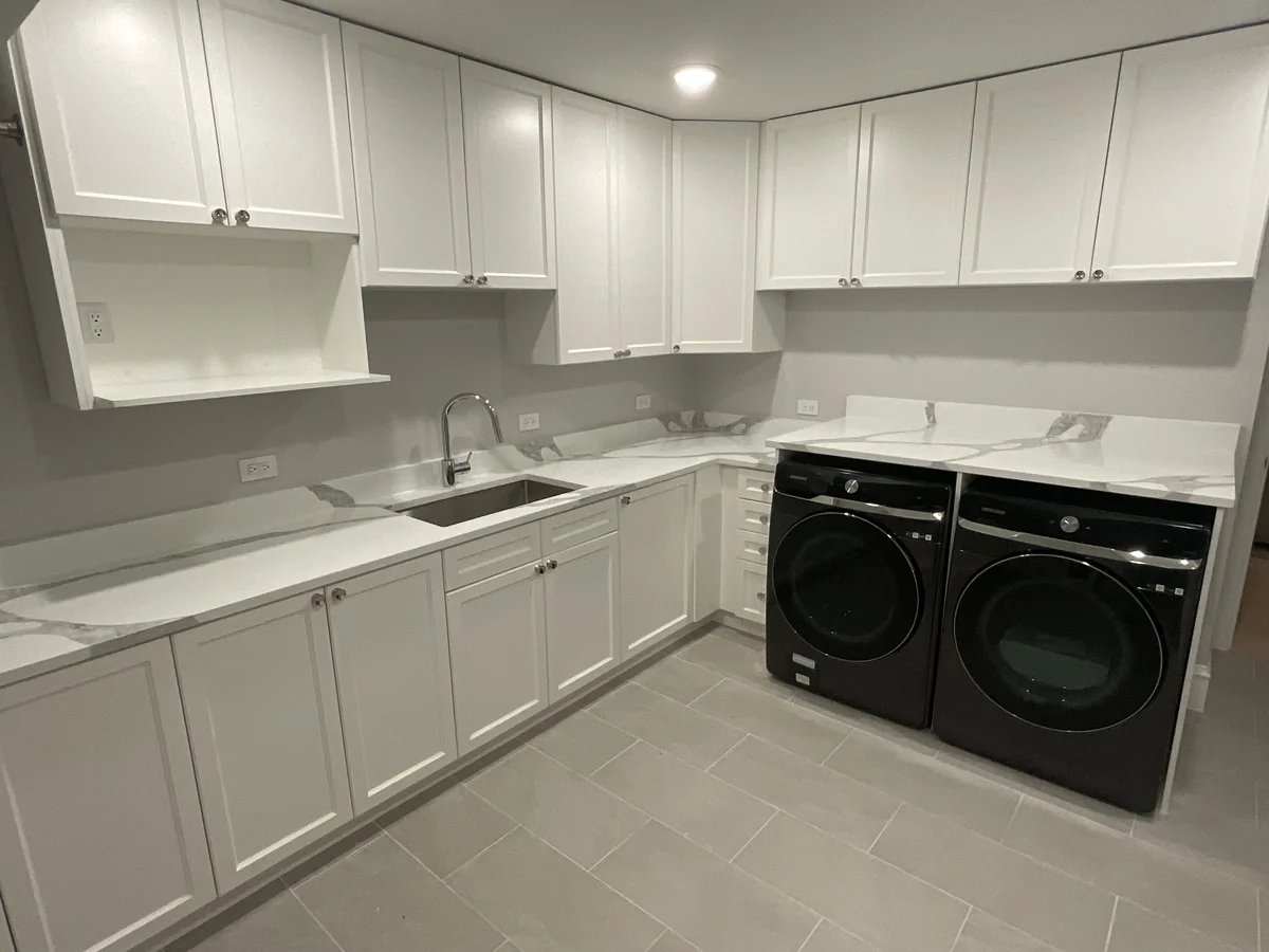 Laundry room with white cabinets, stone counters and a sink beside a washer and dryer