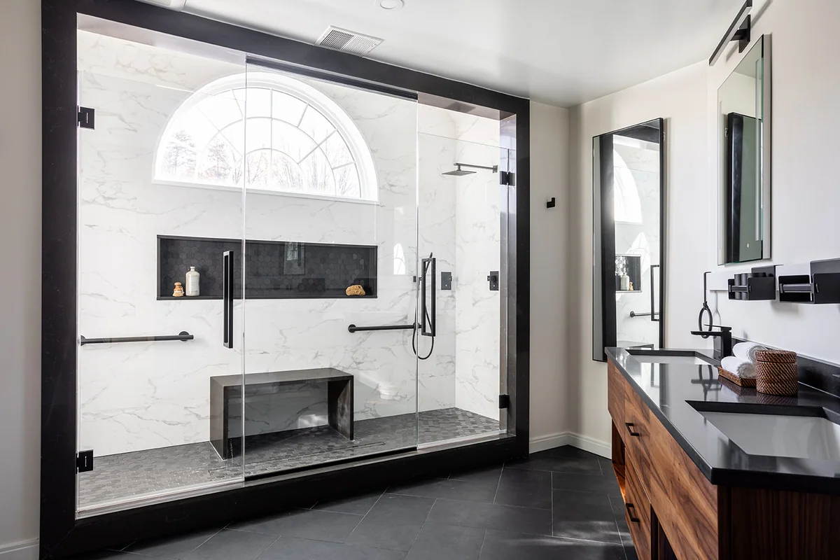 Bathroom with an arched shower window, dark granite door jambs and a granite vanity countertop.